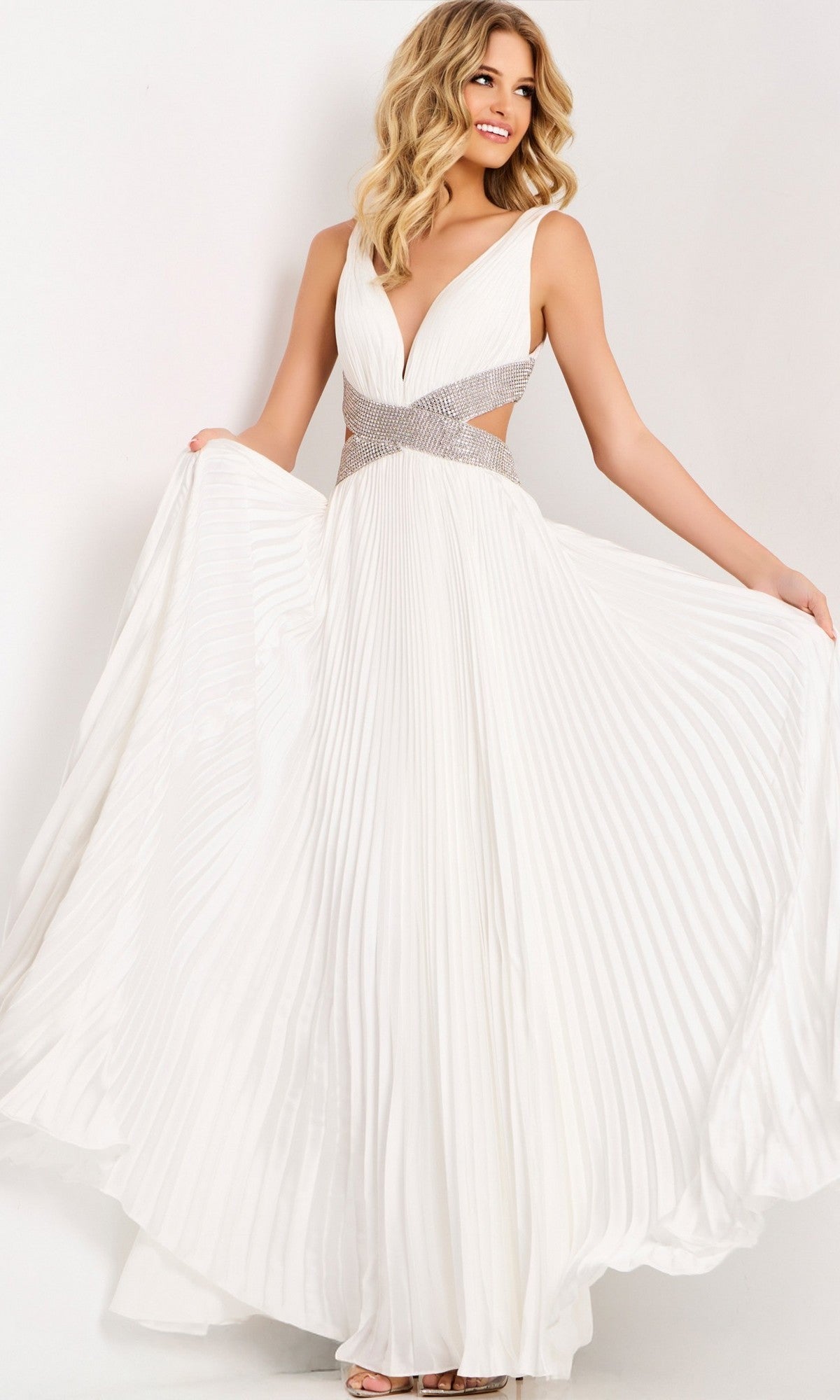 A woman wearing the Jovani 42811 long prom dress in off white, featuring a sleeveless chiffon design with a deep V-neckline and an embellished waistband, stands against a plain background.